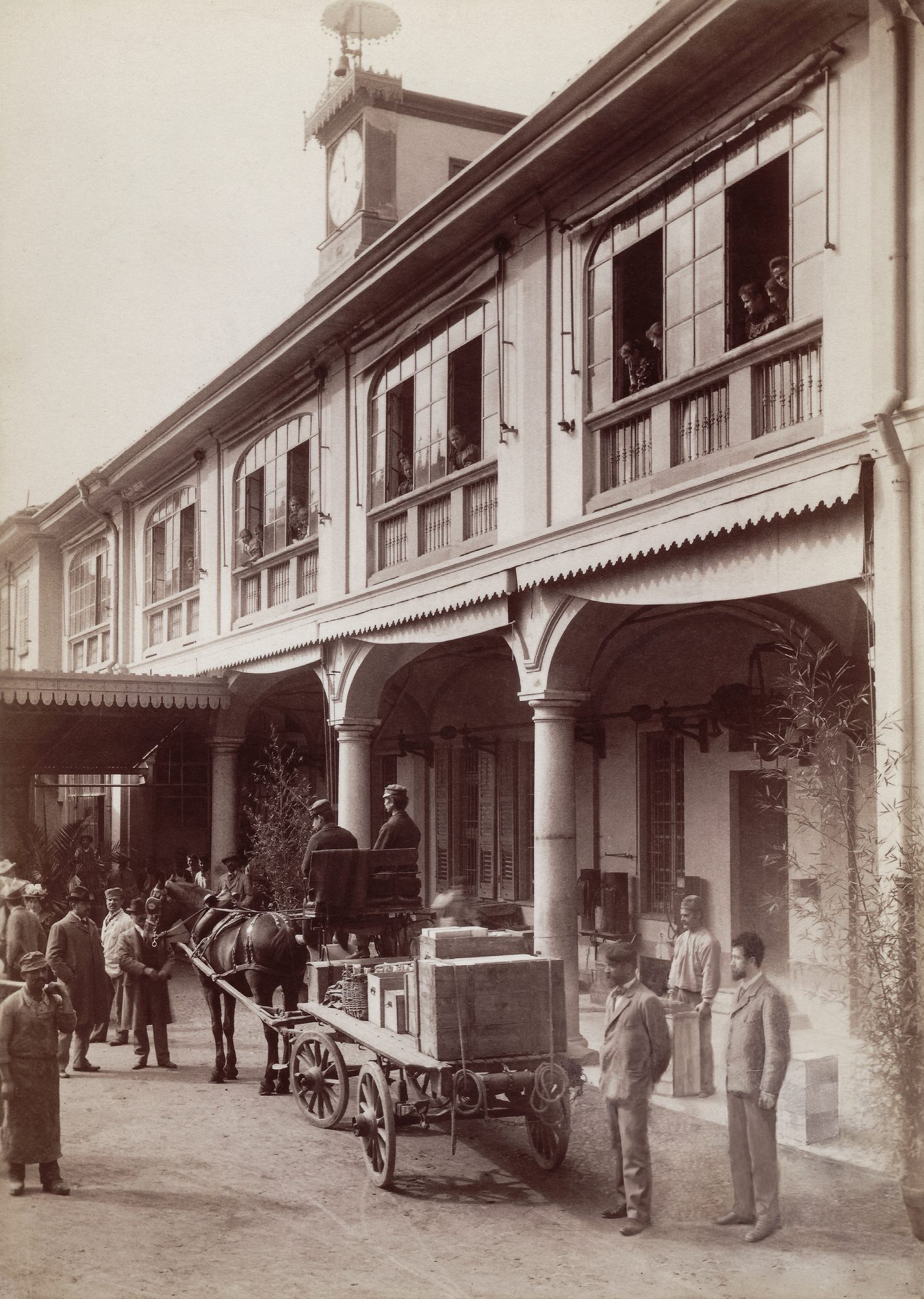 Il cortile porticato dello stabilimento di Corso Loreto, Milano, 1898, con un carro di consegna in caricamento e il personale alle finestre della fabbrica